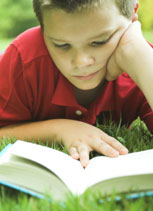 boy lying on grass reading a book